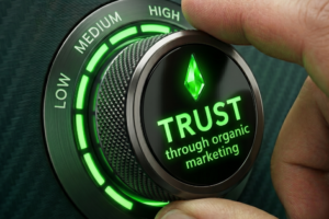 Close up of a metal dial with LowMediumHigh a finger on the knob showing 'TRUST through organic marketing'.